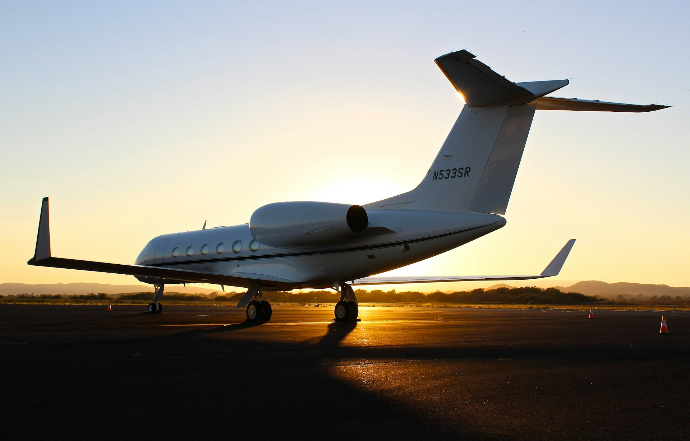 A white private jet on an airport tarmac during the golden hour